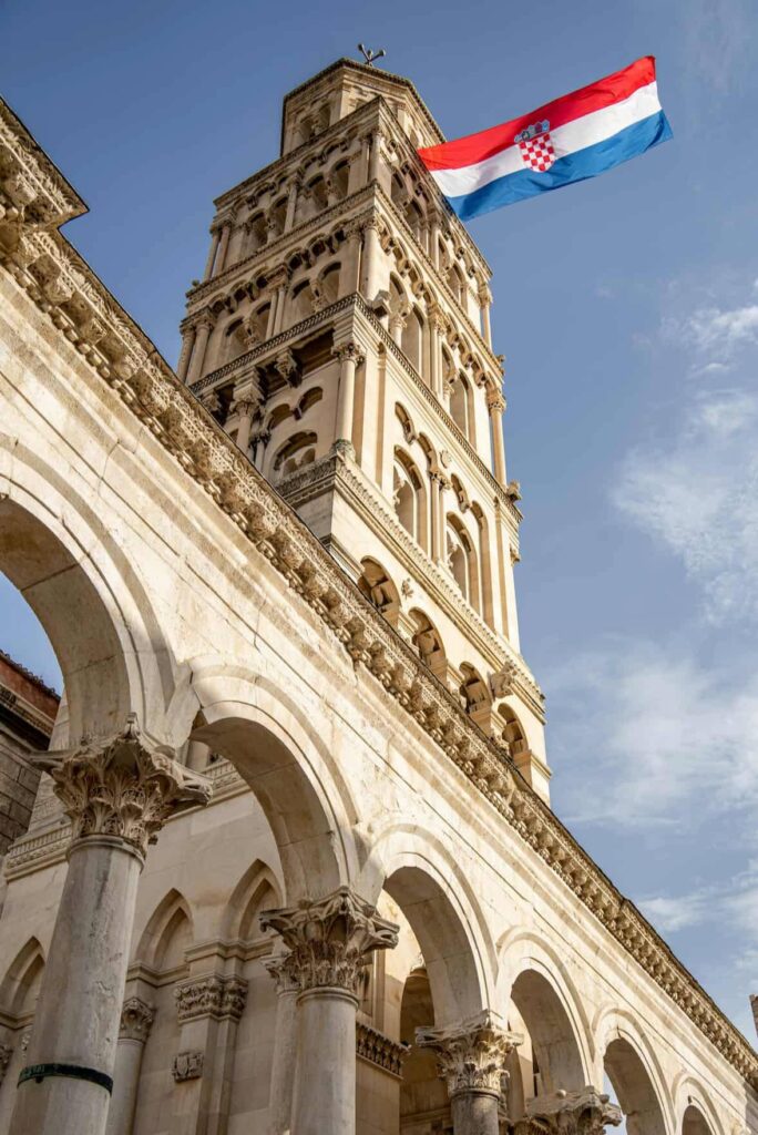 View of the ancient bell tower in Split, Croatia, featuring the national flag.